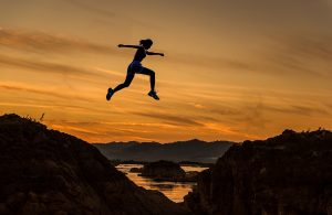 Woman Jumping Across Rocks