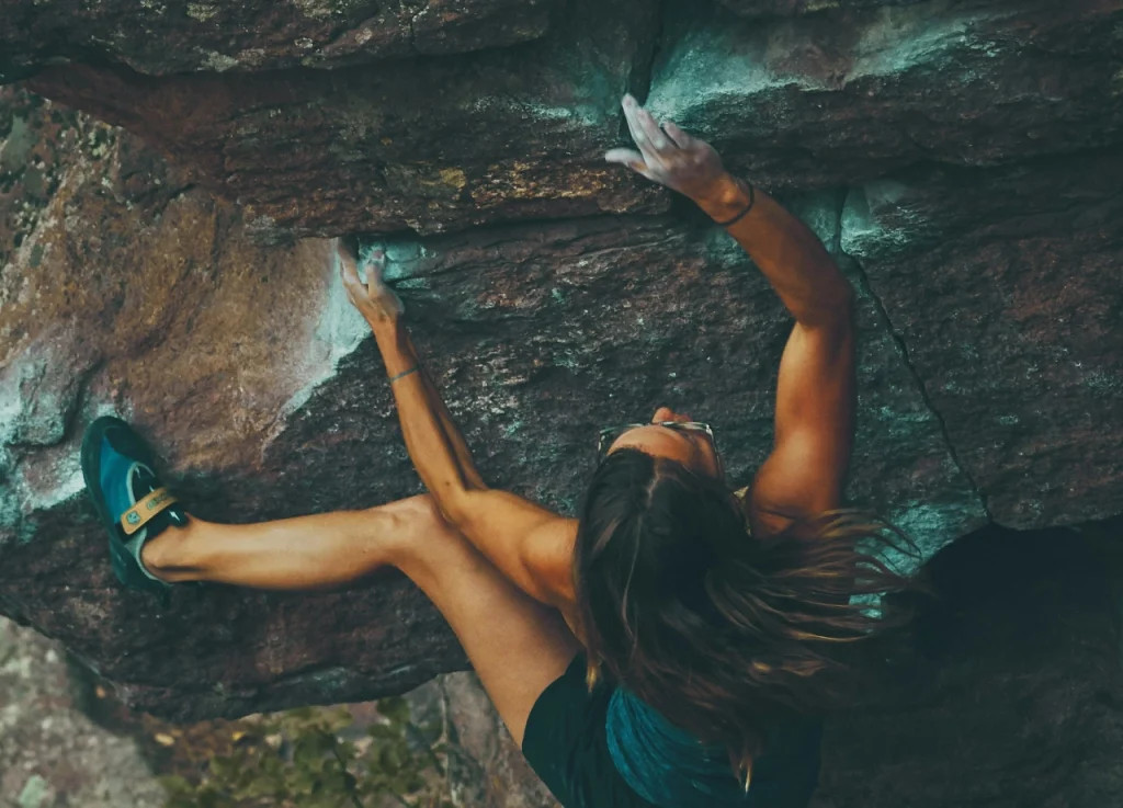 Woman climbing rock, symbolizing research challenges and barriers organizations encounter.